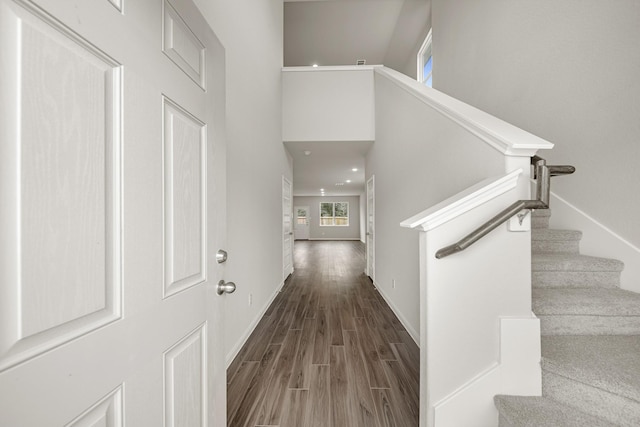 entryway featuring stairs, a high ceiling, wood finished floors, and baseboards