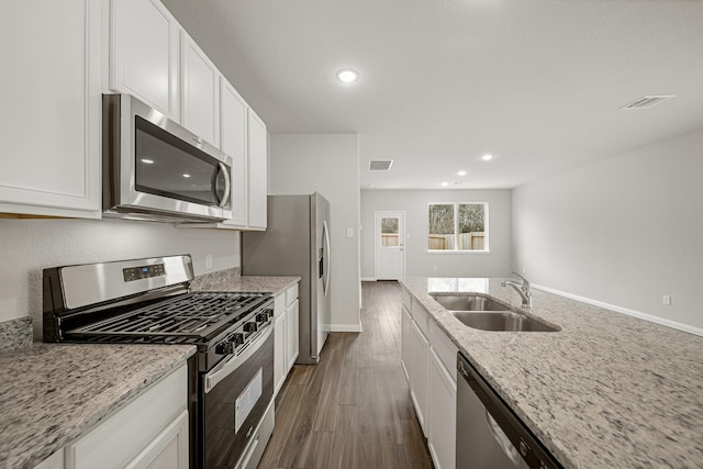 kitchen featuring visible vents, a sink, appliances with stainless steel finishes, white cabinets, and dark wood-style flooring