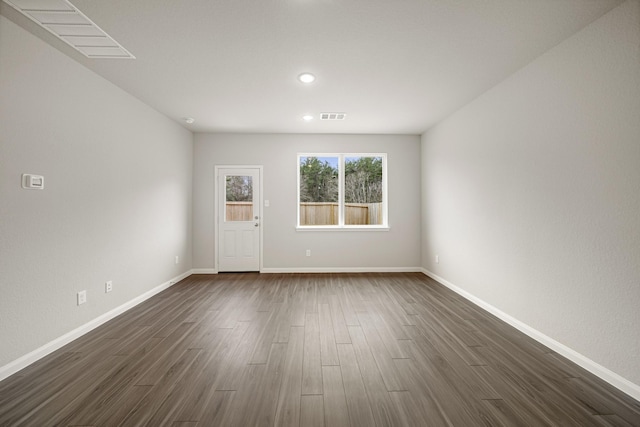 spare room with baseboards, visible vents, and dark wood-style flooring