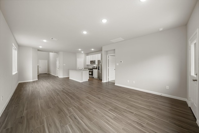 unfurnished living room with recessed lighting, baseboards, and wood finished floors