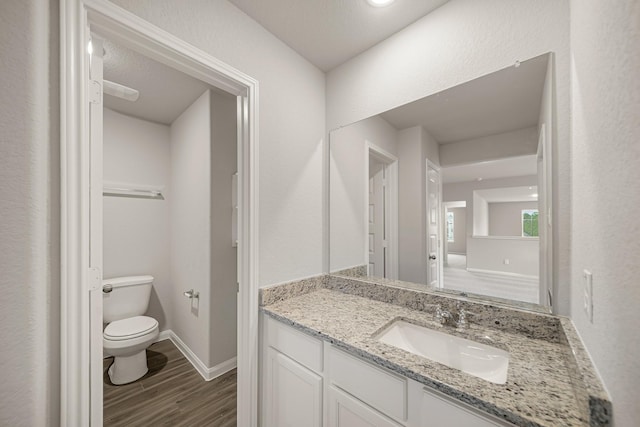 bathroom with toilet, vanity, baseboards, and wood finished floors