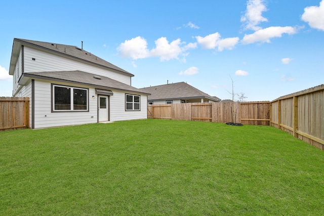 rear view of house featuring a yard and a fenced backyard