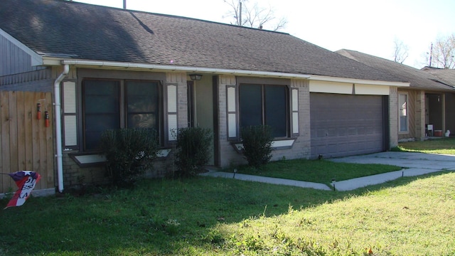 view of front of home featuring a front yard, driveway, roof with shingles, an attached garage, and brick siding