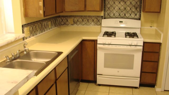 kitchen featuring brown cabinets, a sink, white gas range oven, light countertops, and light tile patterned floors