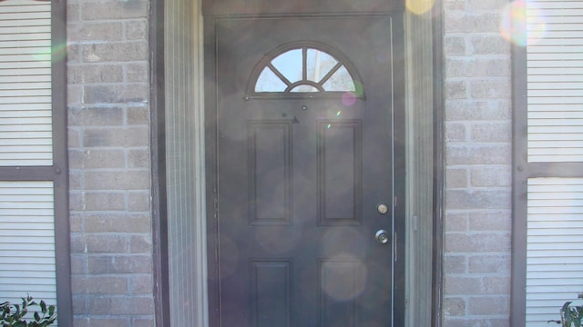 view of exterior entry featuring brick siding