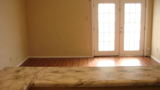 interior space featuring wood finished floors, baseboards, and french doors