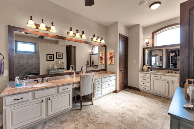 bathroom featuring two vanities, baseboards, and a sink