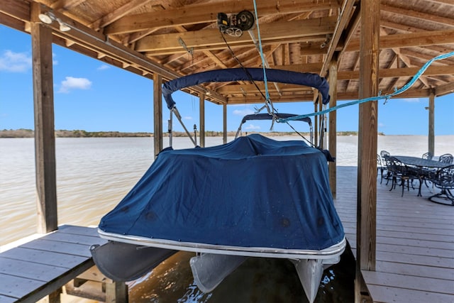 dock area with outdoor dining area and a water view