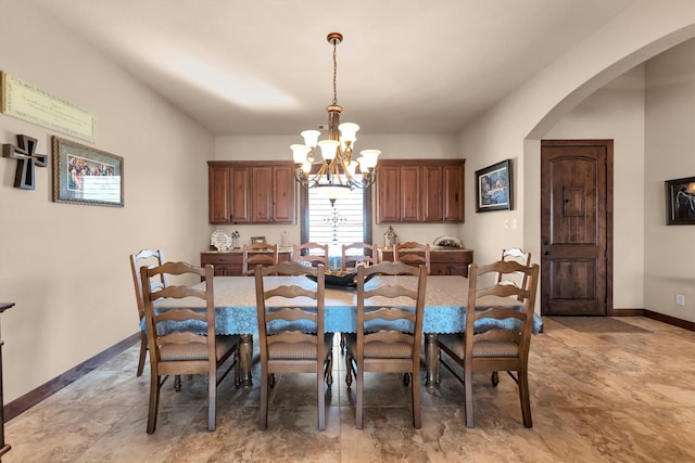 dining room with arched walkways, a chandelier, and baseboards