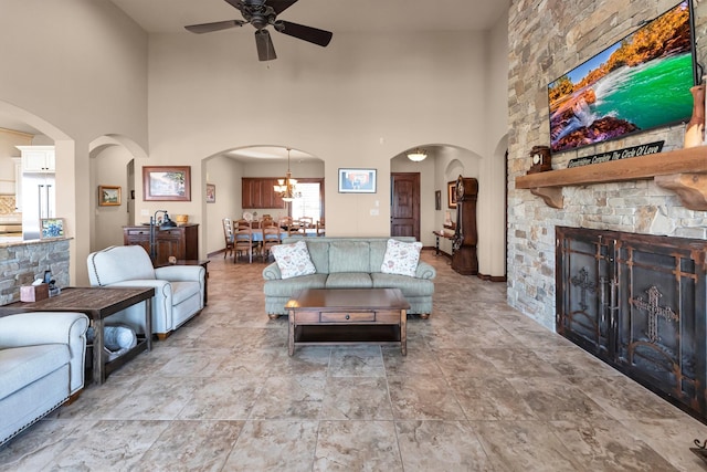 living area with arched walkways, a fireplace, a high ceiling, and a ceiling fan