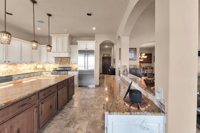 kitchen with visible vents, light stone counters, backsplash, arched walkways, and appliances with stainless steel finishes