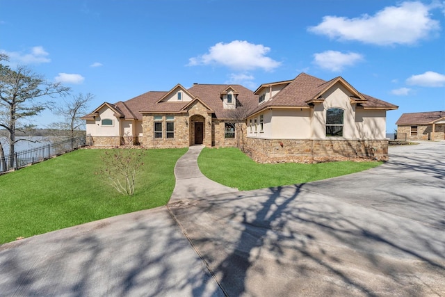 view of front of property featuring stone siding, stucco siding, a front yard, and fence