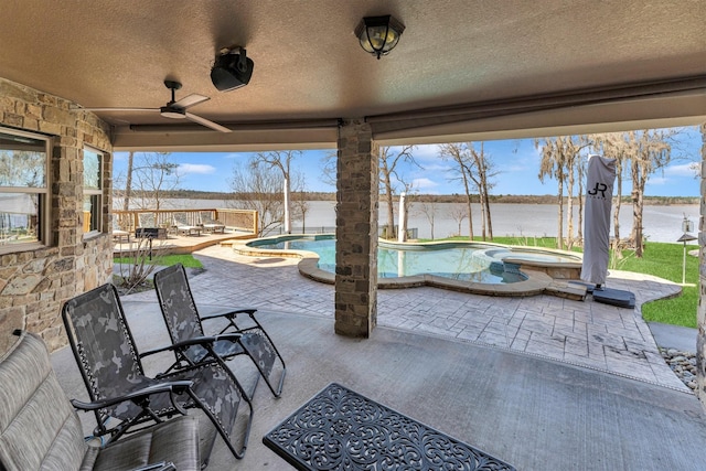 view of patio / terrace featuring a pool with connected hot tub, a ceiling fan, and a water view