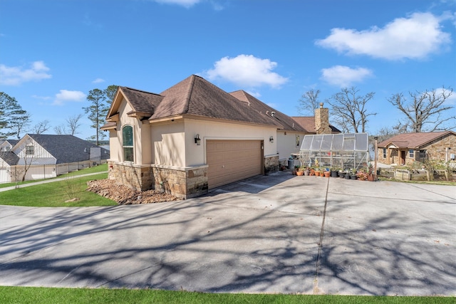 view of property exterior with fence, an exterior structure, stucco siding, a garage, and stone siding