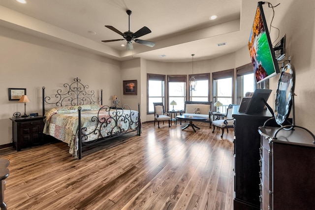 bedroom featuring a tray ceiling, recessed lighting, wood finished floors, and baseboards