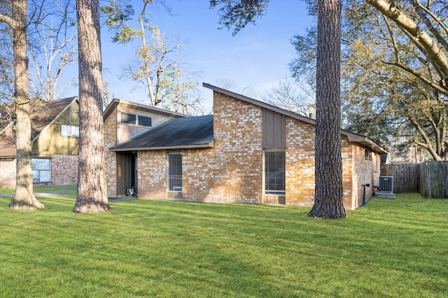 rear view of property with fence, cooling unit, a lawn, and brick siding