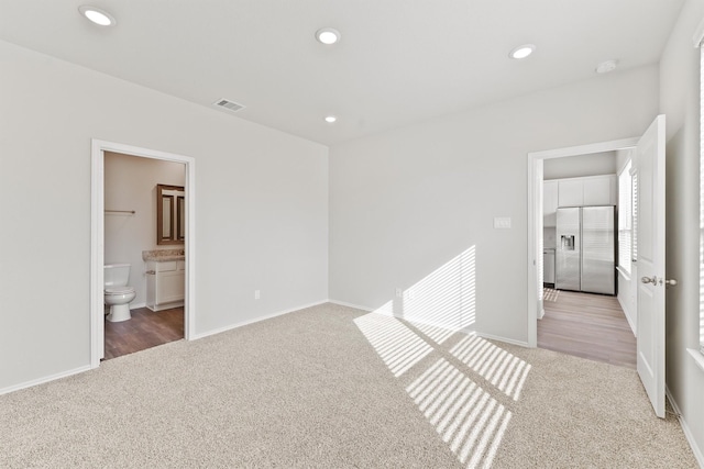 unfurnished bedroom featuring recessed lighting, stainless steel fridge with ice dispenser, visible vents, and carpet floors