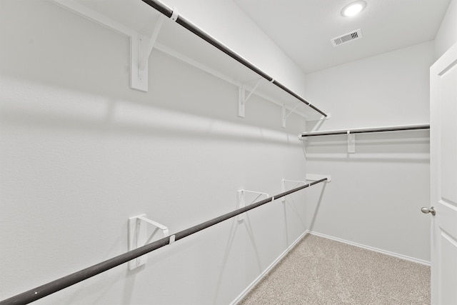 walk in closet with visible vents and light colored carpet