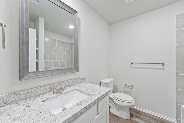 full bath featuring baseboards, toilet, tiled shower, wood finished floors, and vanity