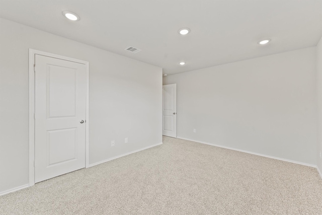 spare room featuring baseboards, recessed lighting, visible vents, and light carpet