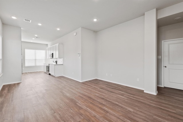 unfurnished living room featuring visible vents, recessed lighting, baseboards, and wood finished floors