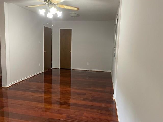 empty room with a ceiling fan, wood finished floors, and baseboards