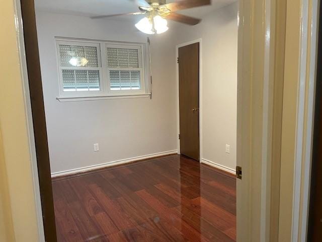 empty room featuring ceiling fan, baseboards, and wood finished floors