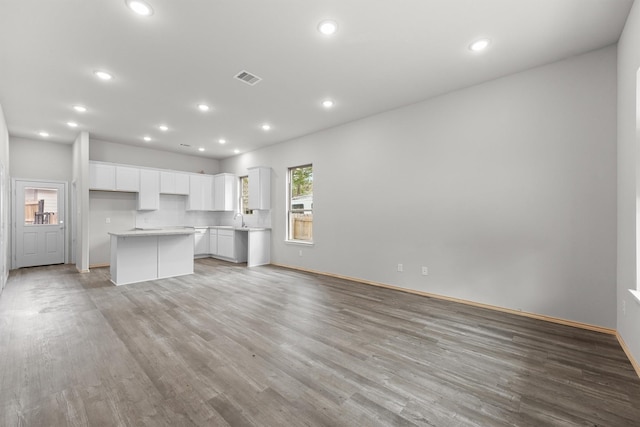 unfurnished living room featuring a sink, light wood-type flooring, visible vents, and recessed lighting