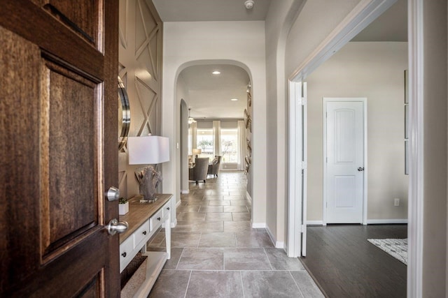 corridor featuring arched walkways and baseboards