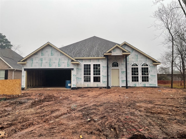 property under construction featuring an attached garage and a shingled roof