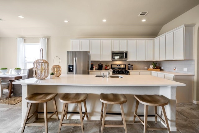 kitchen with decorative backsplash, an island with sink, appliances with stainless steel finishes, and a sink