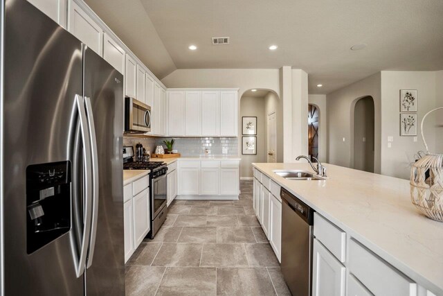 kitchen with visible vents, a sink, appliances with stainless steel finishes, white cabinetry, and tasteful backsplash