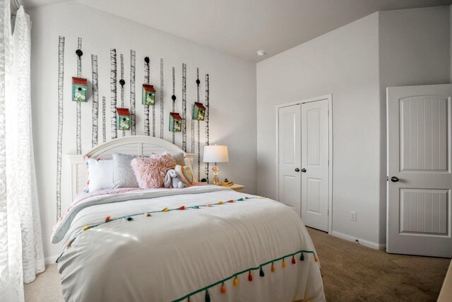 carpeted bedroom with a closet and baseboards