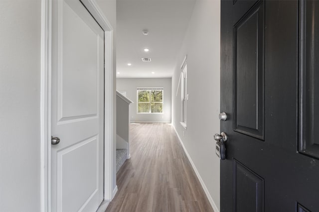 hall with visible vents, baseboards, stairway, light wood-type flooring, and recessed lighting