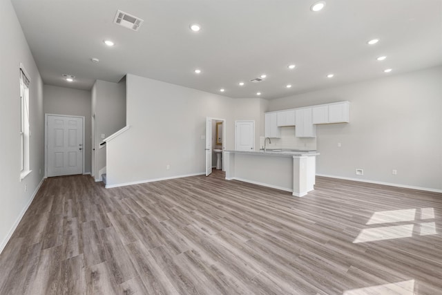 unfurnished living room featuring a sink, visible vents, recessed lighting, and light wood finished floors