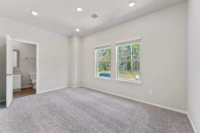 unfurnished bedroom with visible vents, baseboards, carpet flooring, recessed lighting, and ensuite bath