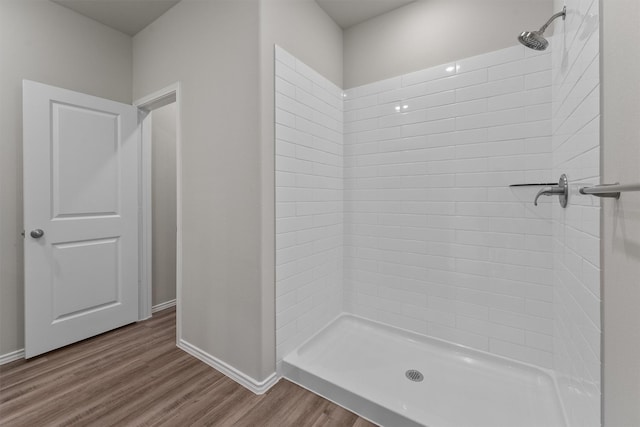 bathroom featuring wood finished floors, a stall shower, and baseboards