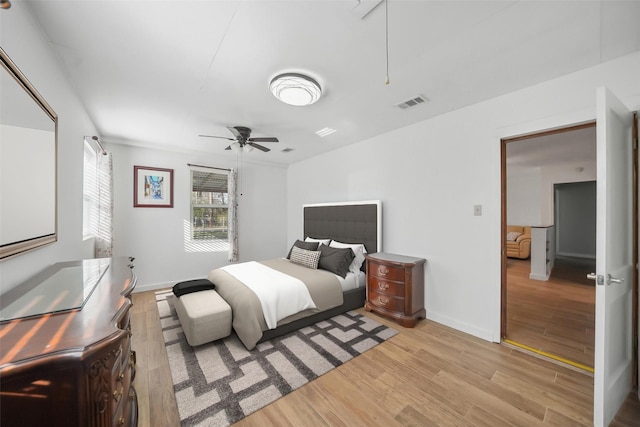 bedroom with visible vents, baseboards, light wood-style floors, and attic access