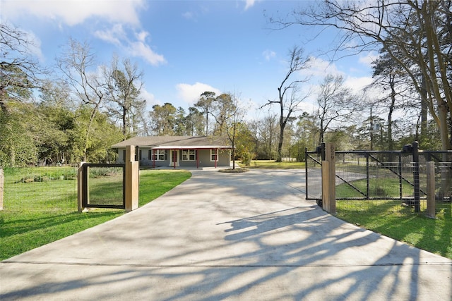 view of front of property with concrete driveway, fence, a front lawn, and a gate