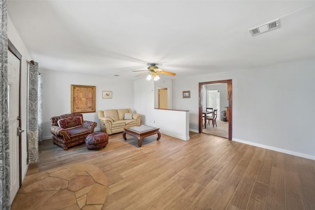 living room featuring visible vents, baseboards, light wood-style floors, and a ceiling fan