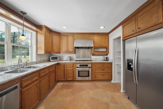 kitchen featuring brown cabinetry, a sink, appliances with stainless steel finishes, and exhaust hood