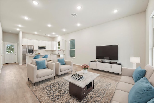 living area with light wood finished floors, visible vents, recessed lighting, and baseboards