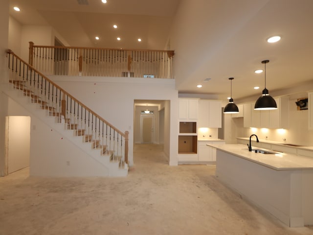 8518 Pier Cove Dr, Cypress, TX 77433 - kitchen featuring recessed lighting, white cabinetry, a towering ceiling, a kitchen island with sink, and light stone counters