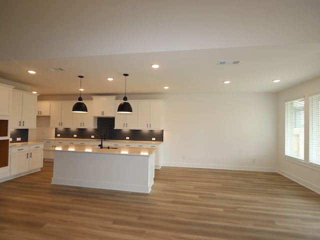 8518 Pier Cove Dr, Cypress, TX 77433 - kitchen with light wood-style flooring, decorative backsplash, recessed lighting, a kitchen island with sink, and white cabinets