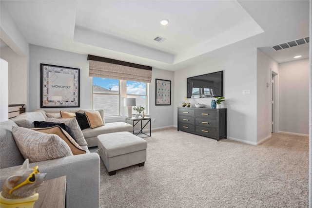 living area featuring visible vents, a raised ceiling, and baseboards