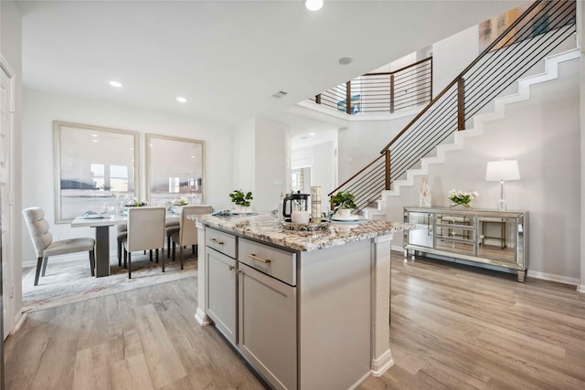 kitchen featuring a kitchen island, light stone countertops, recessed lighting, gray cabinets, and light wood-style floors