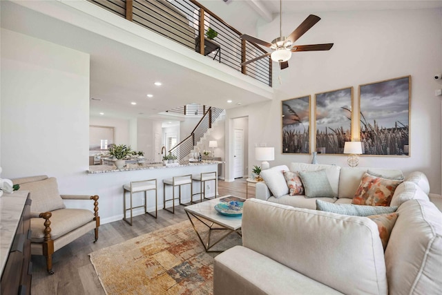 living room featuring beamed ceiling, stairway, recessed lighting, wood finished floors, and high vaulted ceiling