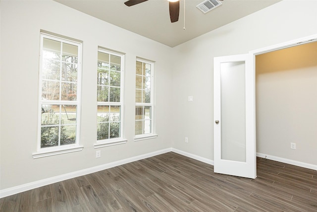 unfurnished room featuring visible vents, baseboards, dark wood finished floors, and a ceiling fan