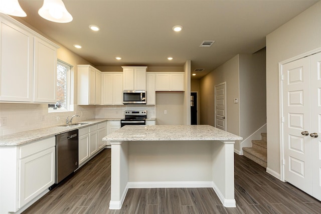 kitchen with visible vents, backsplash, dark wood finished floors, stainless steel appliances, and a sink