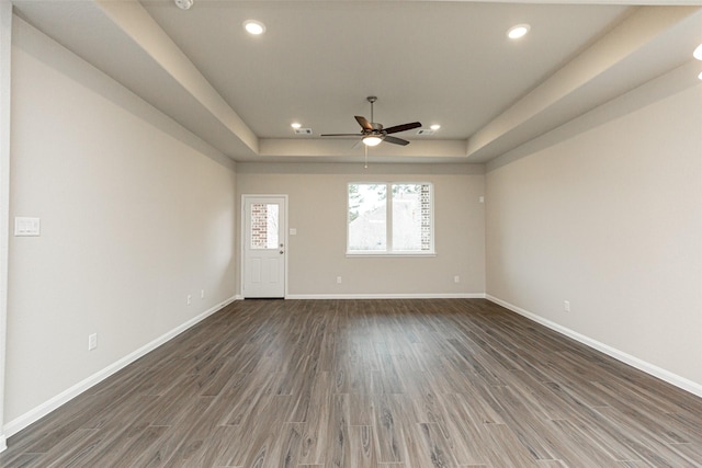 interior space with recessed lighting, baseboards, a tray ceiling, and wood finished floors